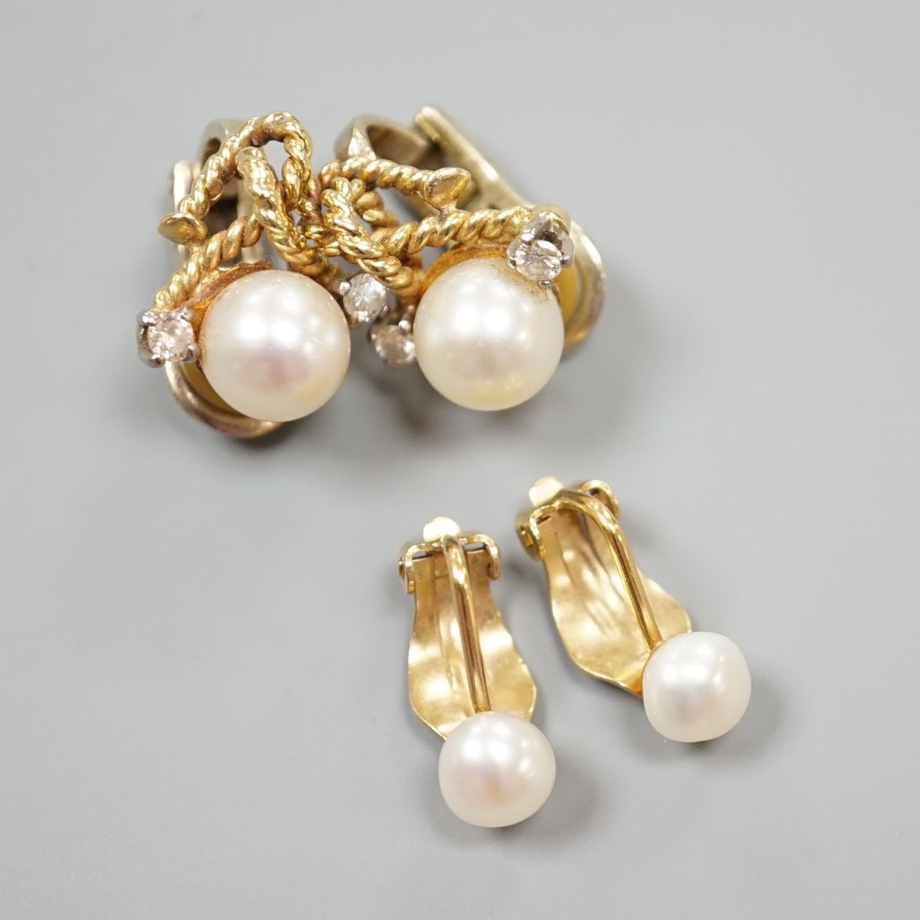 A pair of 20th century yellow metal, diamond and cultured pearl set ear clips, 18mm and a pair of yellow metal and cultured pearl set ear clips, gross 10.3 grams.